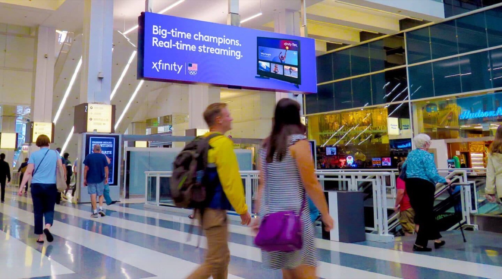 A large screen over a train station concourse